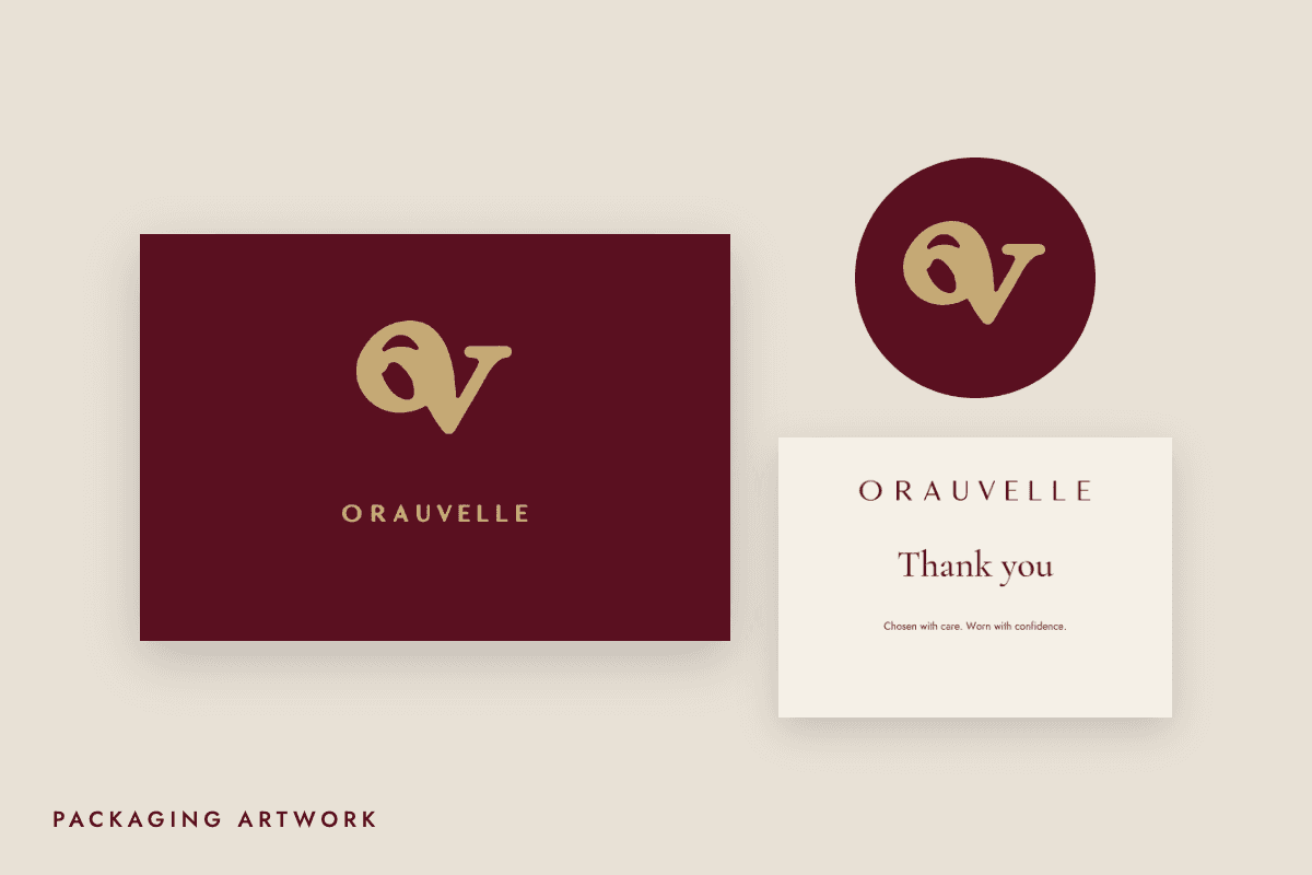 Orauvelle packaging artwork: burgundy box lid with champagne monogram, seal sticker and thank-you card